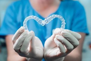 woman holds invisalign aligners in the shape of a heart for love