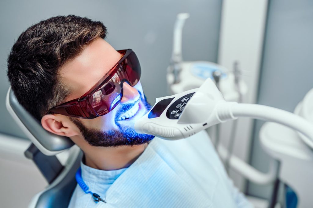Man with protective glasses getting a teeth whitening treatment.