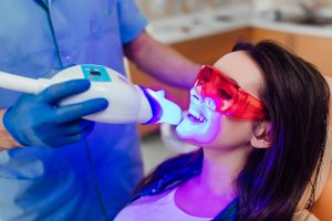 Dentist applying LED light on woman's teeth for teeth whitening 