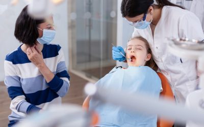 Kid in a dentist chair with mom getting her family dental care